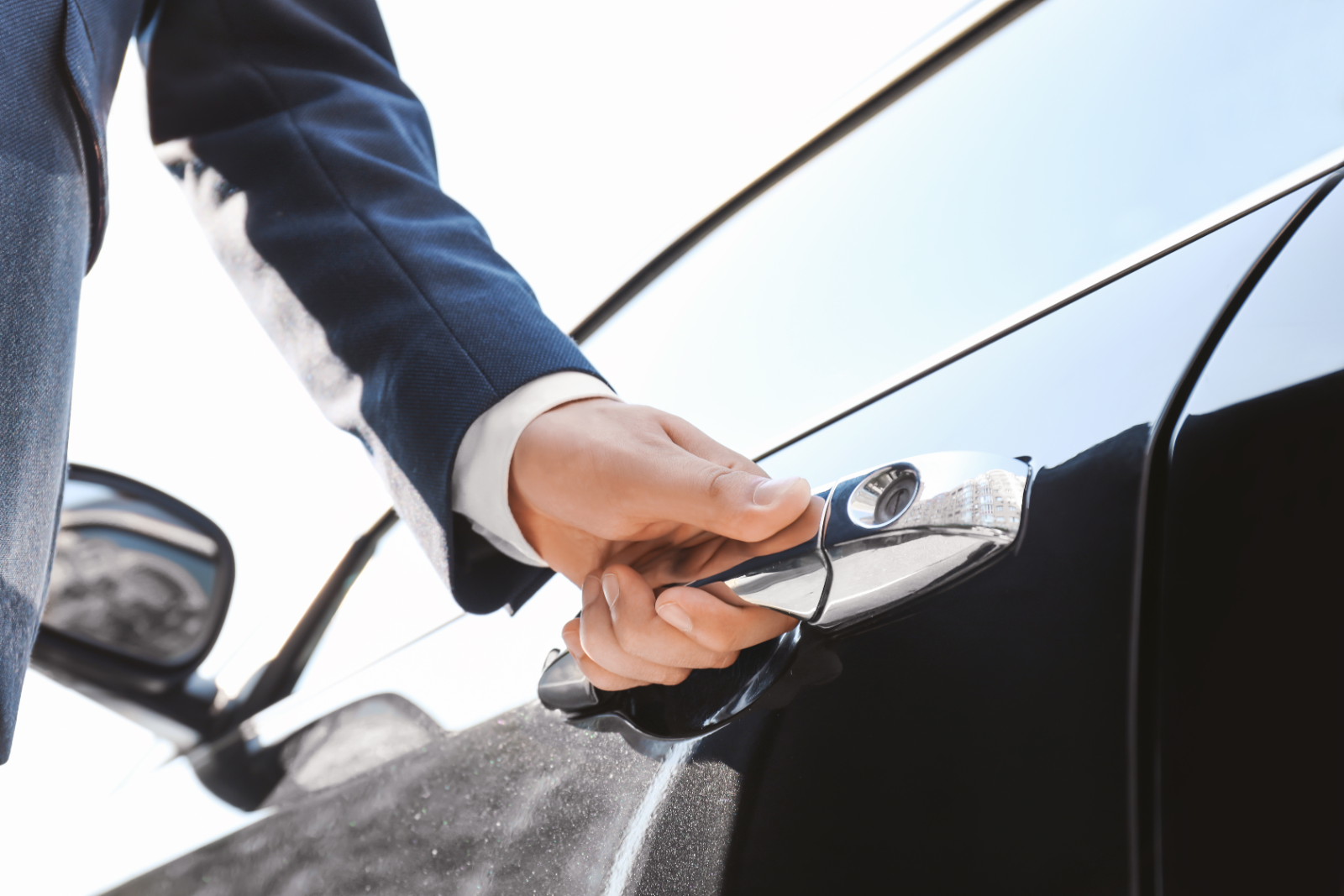 A chauffeur opening a car door for a traveller
